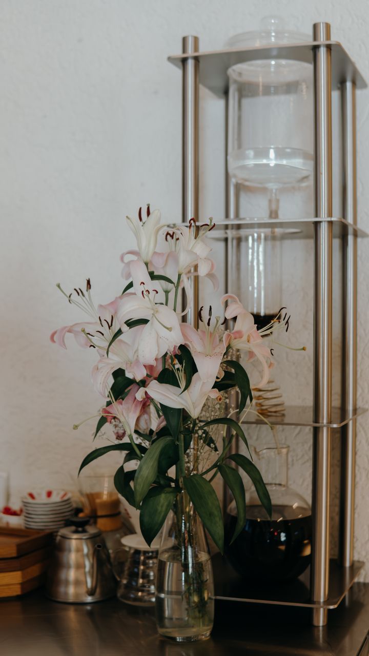 Small vase of fresh daisies placed on a coffee bar hutch shelf