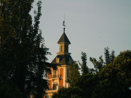 Free Charming architectural tower surrounded by lush trees, evoking a serene and picturesque atmosphere. Stock Photo