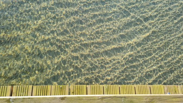 A tranquil view of rippling water next to a wooden pier, evoking a sense of serenity.