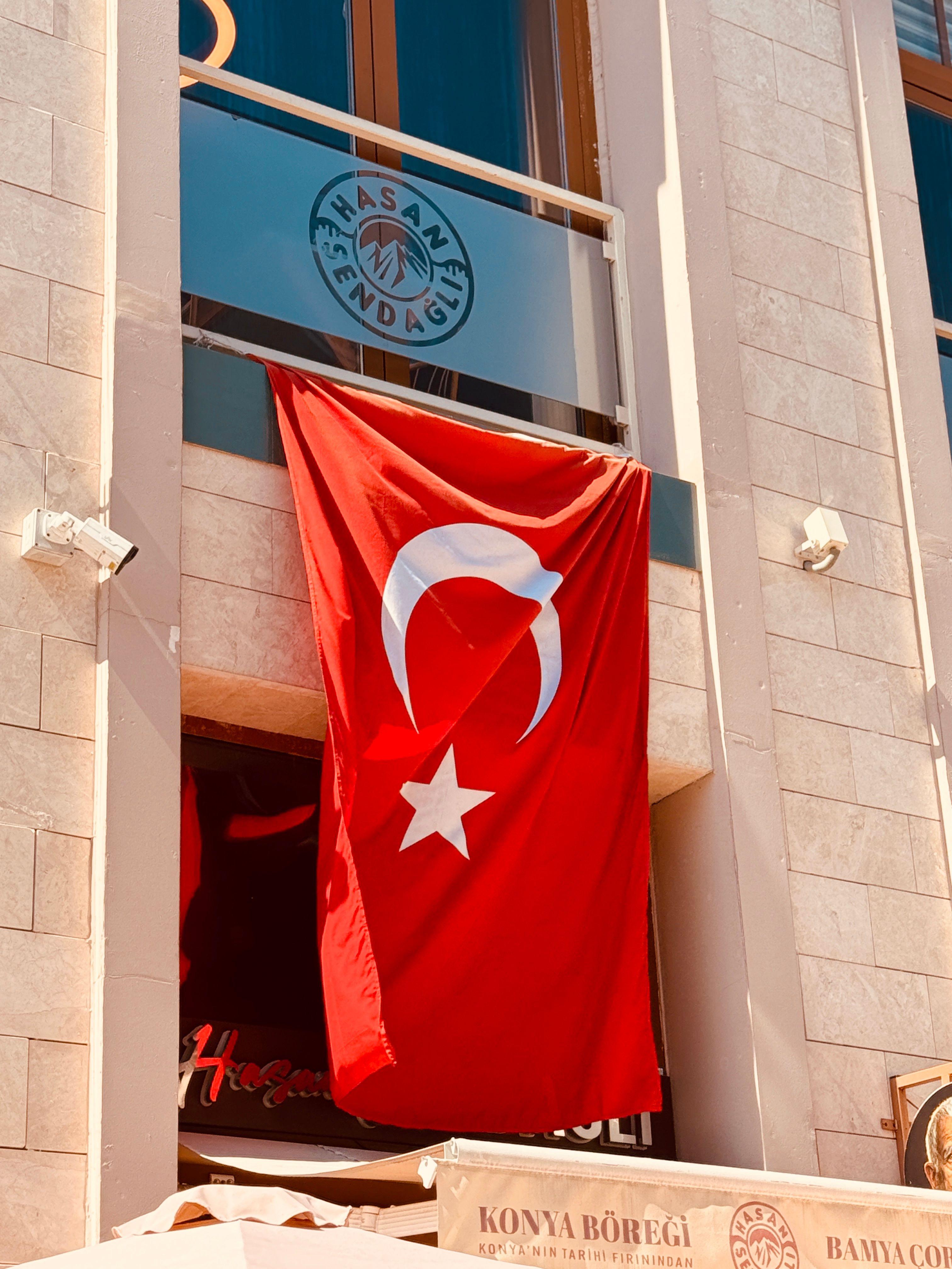 A Turkish flag hangs prominently on a modern building facade in daylight.