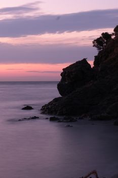 A serene coastal scene featuring a dramatic cliff against a colorful sunset sky, perfect for tranquil themes.