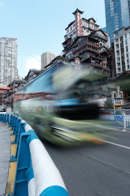 Blurry city bus passes traditional architecture in Chongqing, China.
