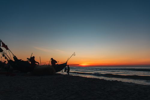 Free Fishermen silhouette against sunrise, capturing the serene coastal beauty of Quảng Trị, Vietnam. Stock Photo