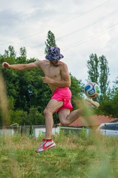 Energetic scene of a man in sporty attire skillfully kicking a soccer ball in a lush field.
