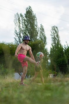 Shirtless man in pink shorts playing soccer outdoors in Ohrid.