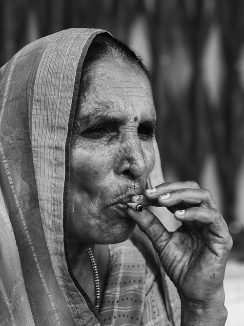 Free Black and white portrait of a senior woman in traditional attire smoking a bidi. Stock Photo
