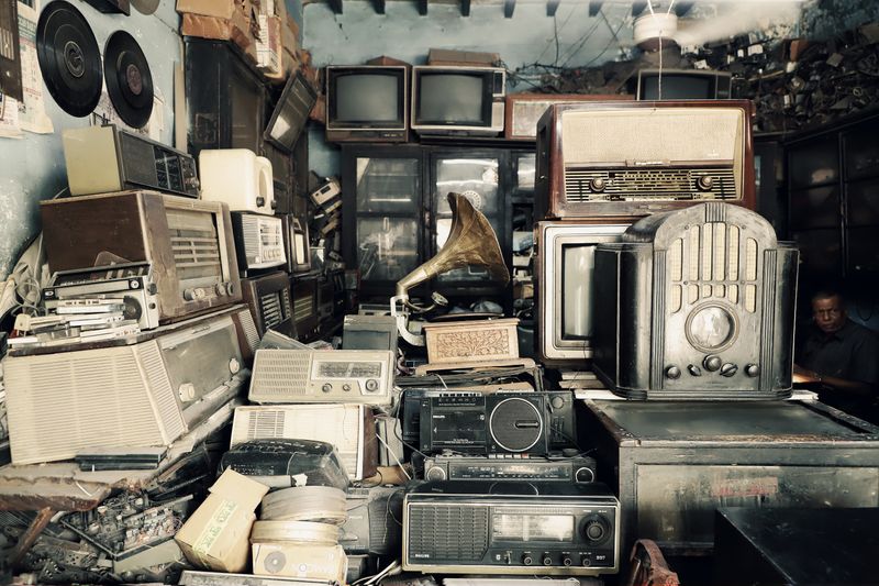 An array of vintage electronics, radios, and a gramophone in an antique shop with a nostalgic atmosphere.