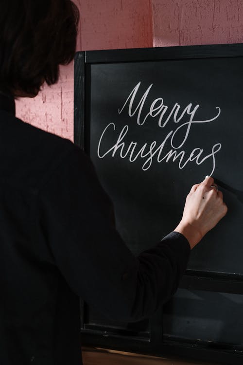 Person in Black Long Sleeve Shirt Writing on Black Board