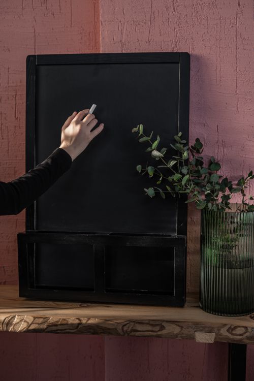 Free A hand writing with chalk on a blackboard, accompanied by a green plant, set indoors. Stock Photo