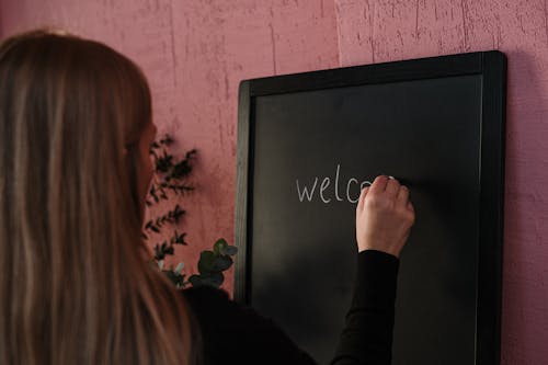 Woman in Black Long Sleeve Shirt Writing on the Chalkboard