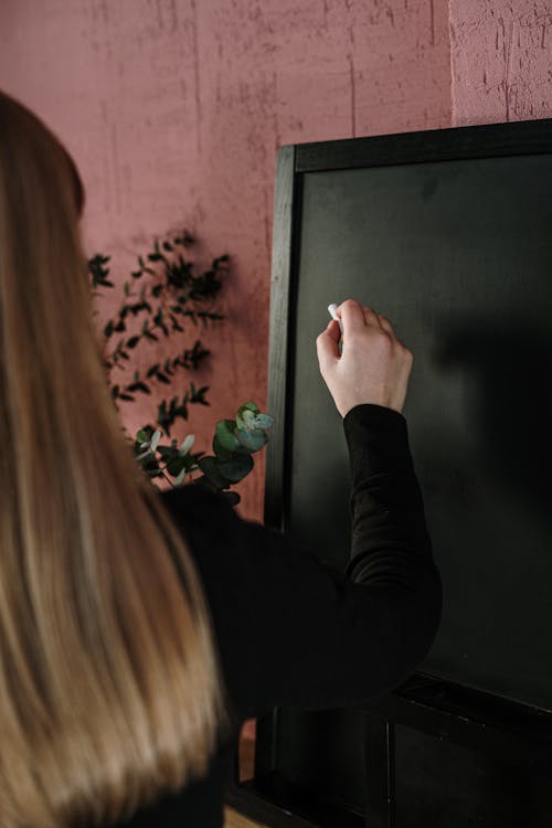 Free Woman in Black Long Sleeve Shirt Writing on the Chalkboard Stock Photo