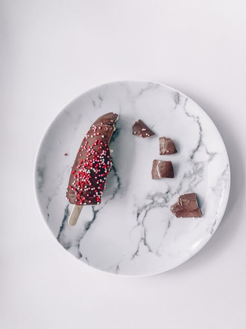 Top view of pieces of delicious chocolate ice cream placed on marble plate on white table