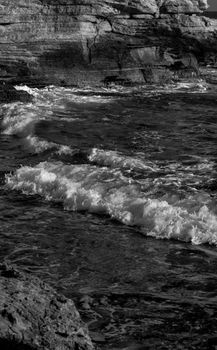 Artistic black and white photo of waves crashing on a rocky shore in Cairo, Egypt.