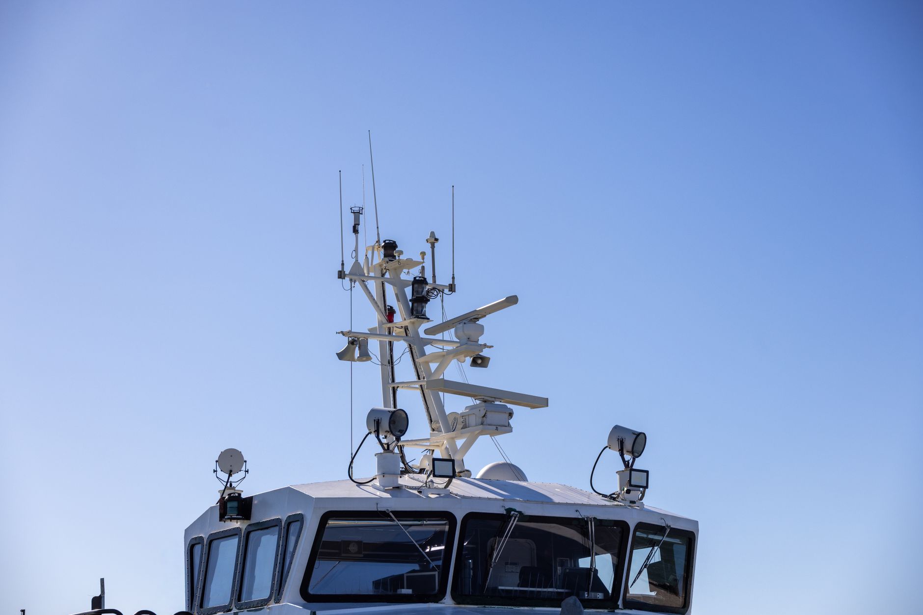 Detailed view of a modern boat's radar and aerial equipment with clear blue sky background.