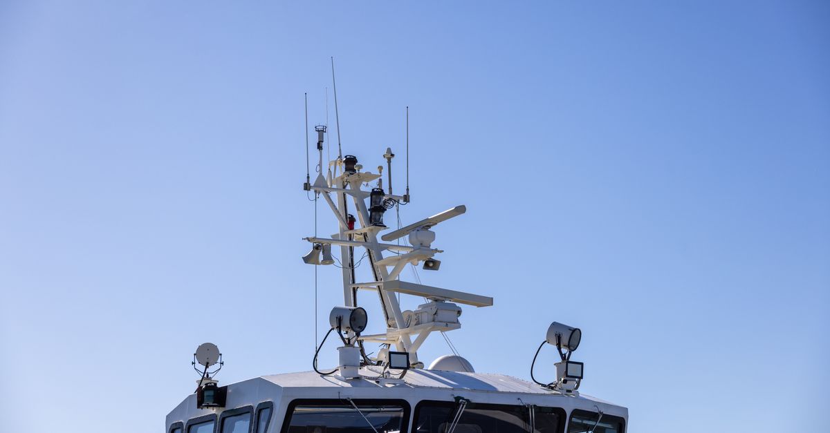 Detailed view of a modern boat's radar and aerial equipment with clear blue sky background.