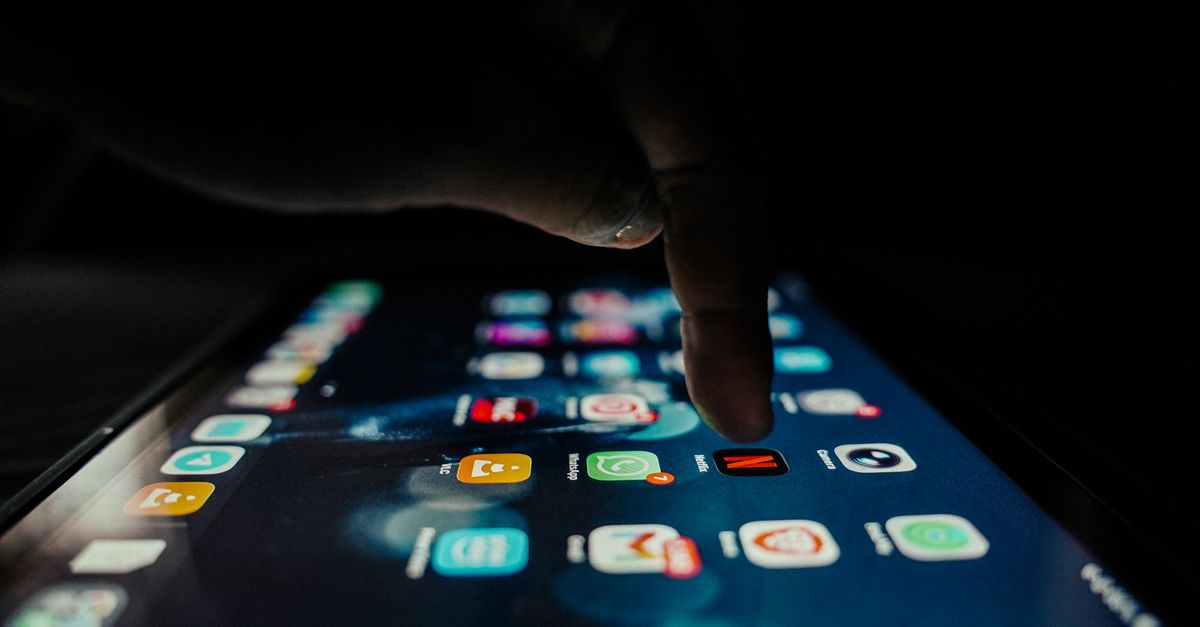 A person looking at a smartphone with a glowing bank app at night, clock showing 10pm, dim lighting