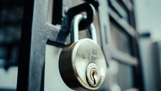 Steel padlock securely fastened on a gate, symbolizing security and protection.