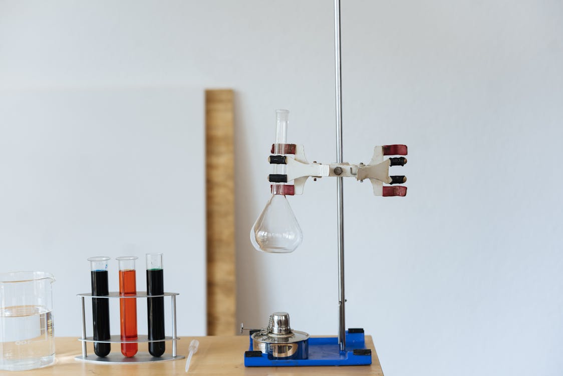 Free Chemical test with empty flask mounted on ring stand while burner under flask and tubes filled with reagents in modern lab Stock Photo