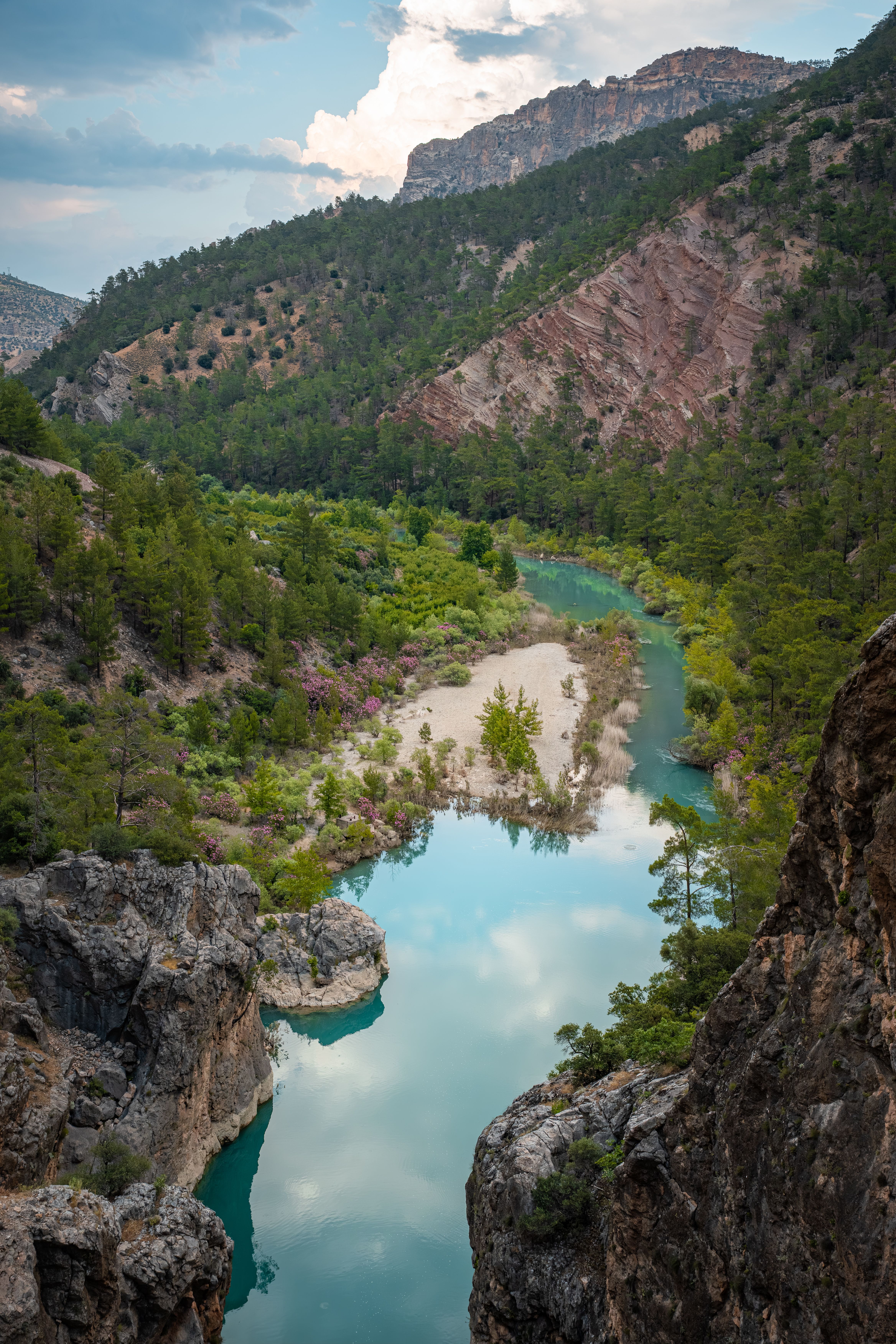 A serene river flowing through lush greenery and rugged mountains in Mersin, Türkiye.