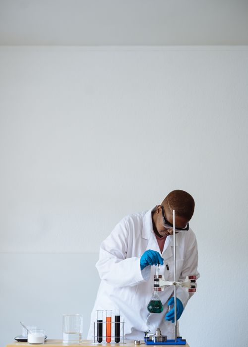 Free Concentrated laboratory technician wearing white coat and gloves and using pipette to take care of liquid while working in chemistry lab Stock Photo