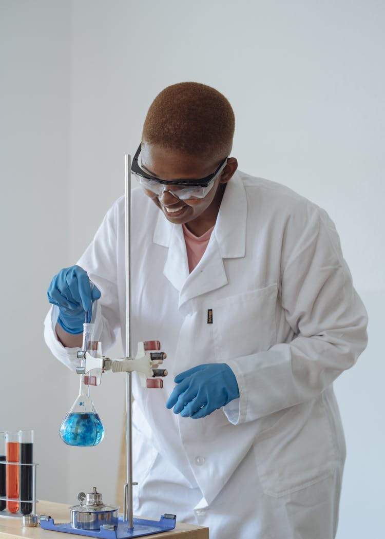 Smiling Scientist Examining Chemical Liquid In Modern Lab