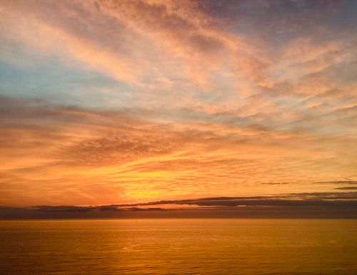 Free Capture the mesmerizing hues of a sunset over a calm ocean surface. Stock Photo