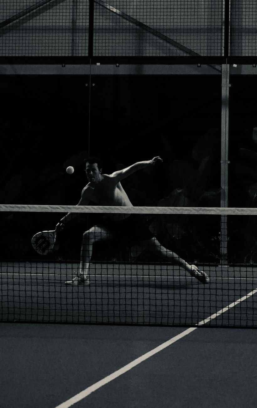 Padel player striking the ball in dramatic light