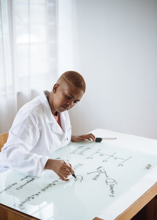 Free Focused African American teenage chemist working on formula in scientific center Stock Photo