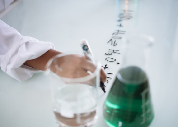 Crop Chemist Taking Science Notes On Whiteboard During Experiment With Liquids