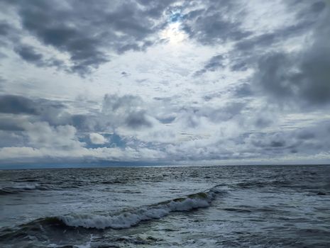 A captivating view of a cloudy ocean scene captured at dusk, showcasing waves and a moody sky.