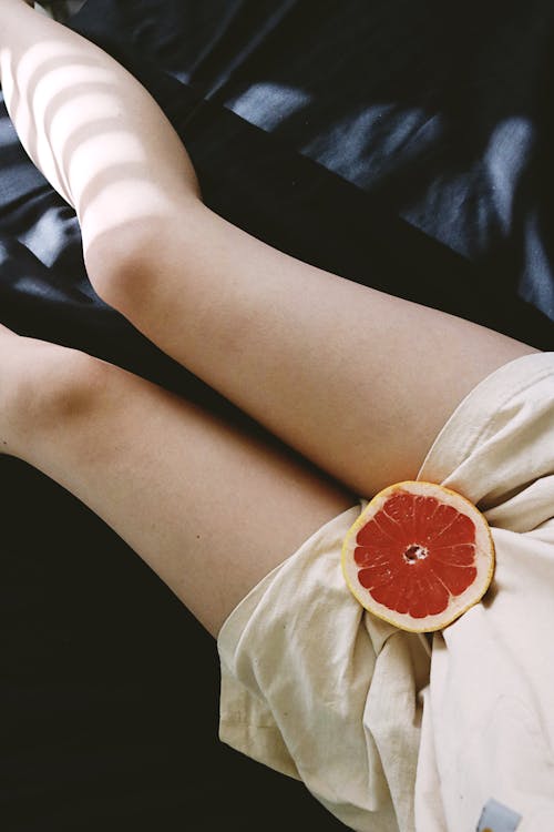 Sliced Grapefruit in Between a Person's Legs