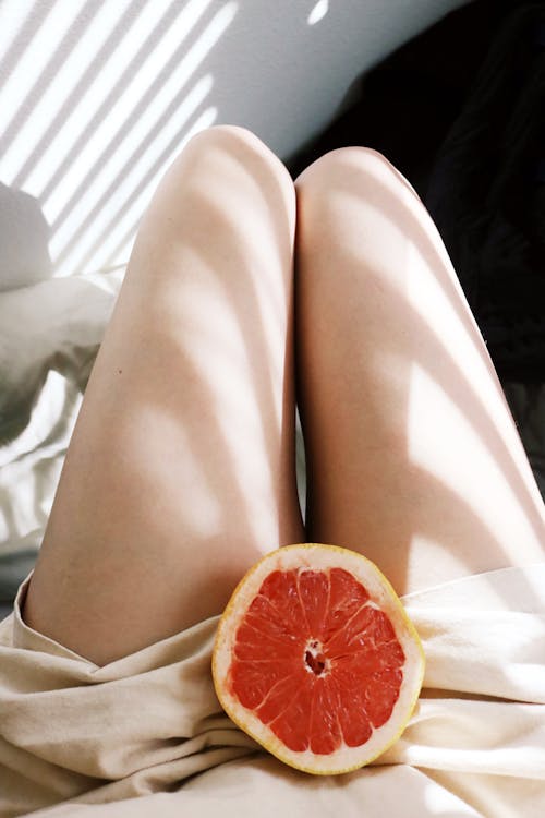 A Person with a Sliced Grapefruit in Between Her legs