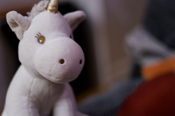 Gros plan sur une peluche licorne blanche, fond en flou artistique