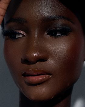 Close-up portrait of a woman with elegant makeup, showcasing her radiant skin and bold eyeliner.