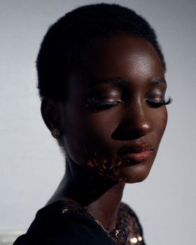 A striking close-up portrait of a Black woman showcasing elegant bold makeup with a serene expression.