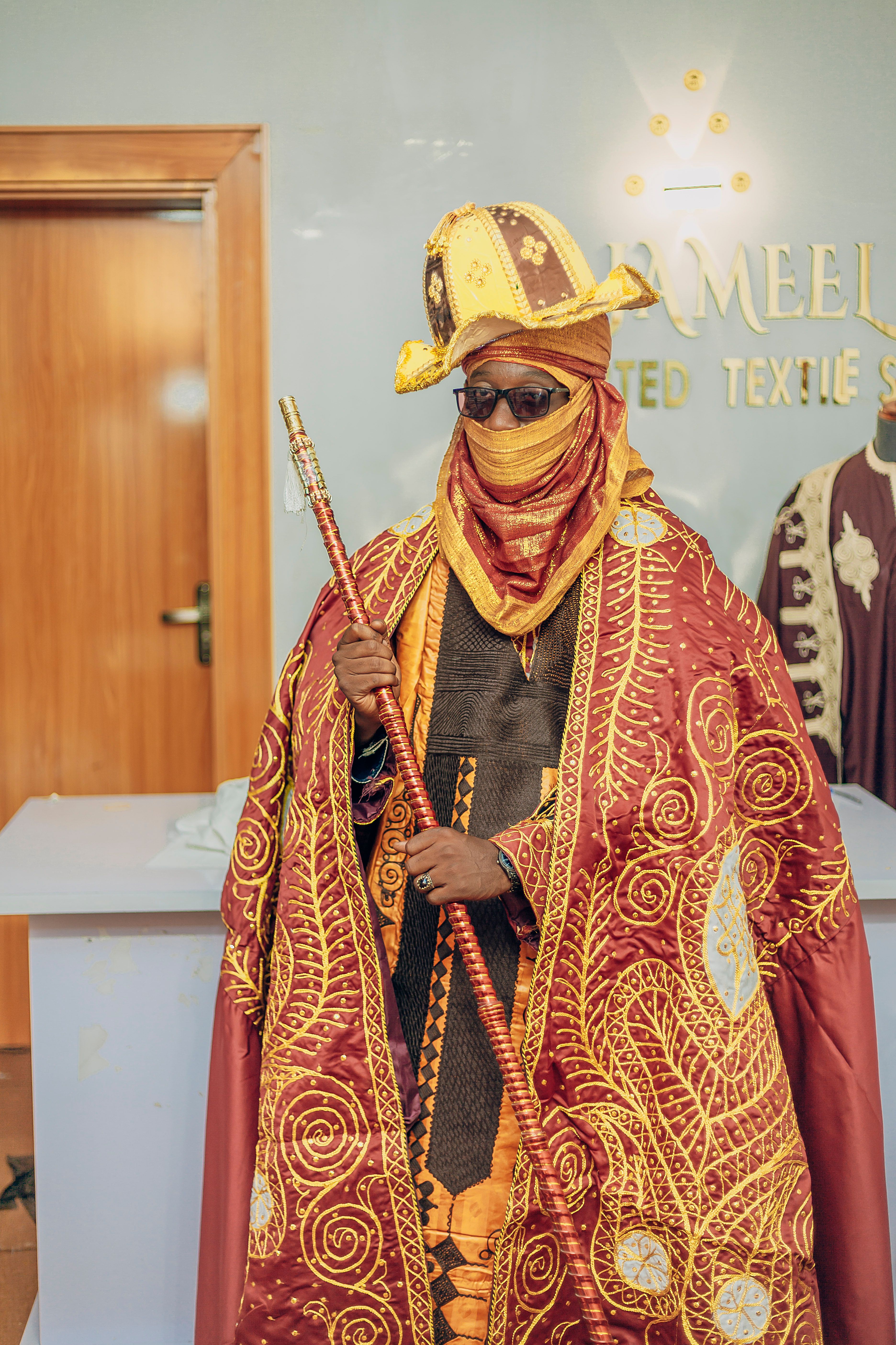Majestic portrait of a man in vibrant African robe and headgear indoors.