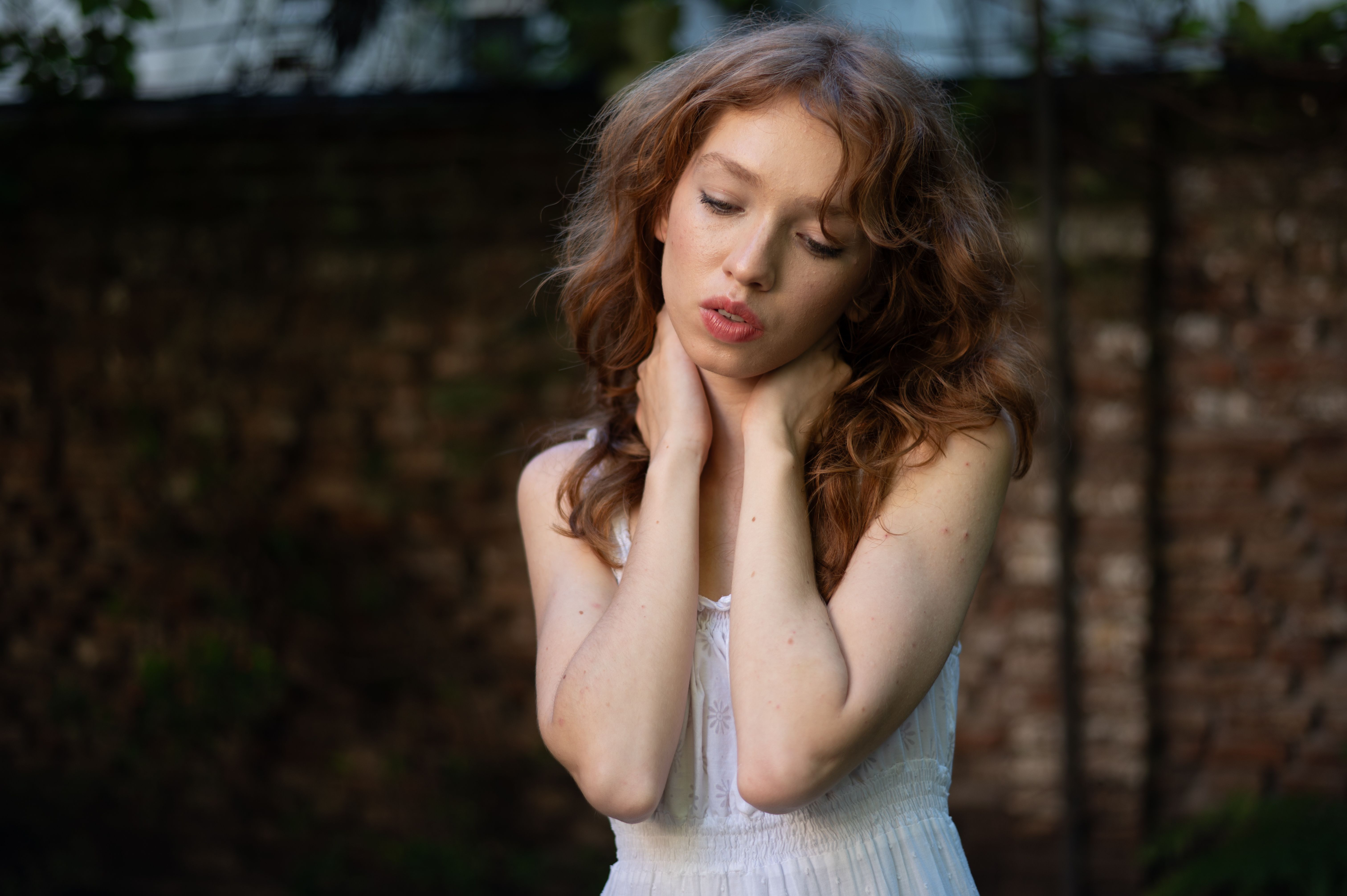 Serene portrait of a woman with red hair in outdoor natural setting.