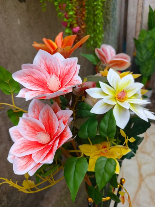 Free A detailed view of colorful artificial flowers with lush greenery in an outdoor setting. Stock Photo