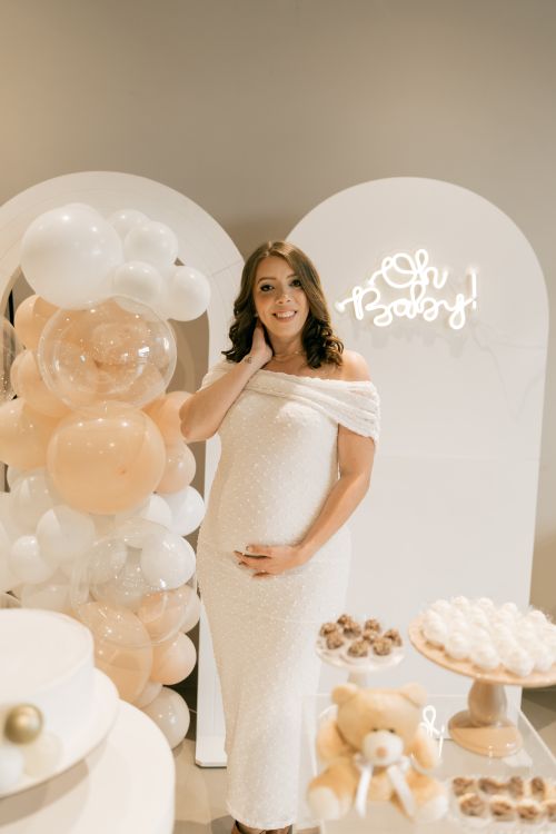 Free Pregnant woman in white dress at an elegantly decorated baby shower with balloons and pastry. Stock Photo