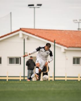 Dynamic action shot of a soccer player kicking a ball during a daytime match.