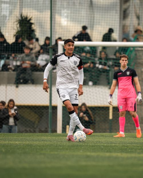 Free Soccer players on a field during a match, one in white uniform dribbling the ball. Stock Photo