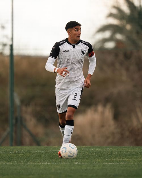 Free A young male soccer player dribbles the ball during a match wearing a white and black uniform. Stock Photo