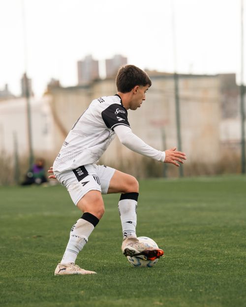Free Action shot of a teenage soccer player dribbling on a grassy field outdoors. Stock Photo