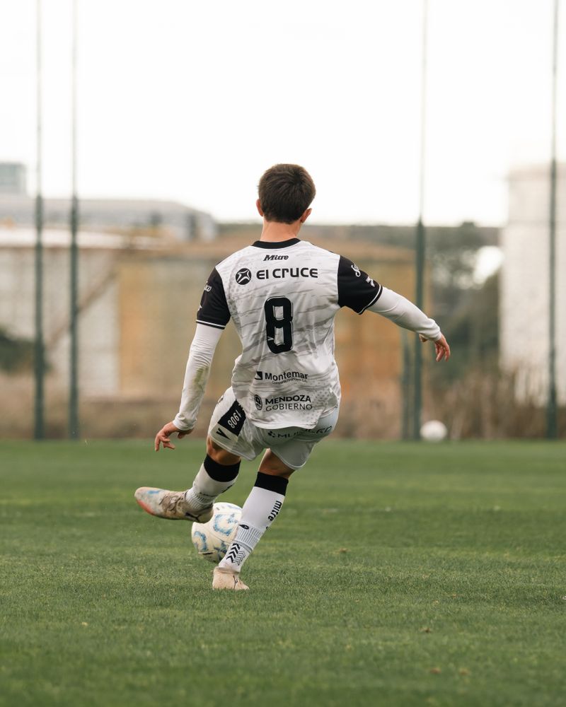 Rear view of a soccer player striking the ball on a green field