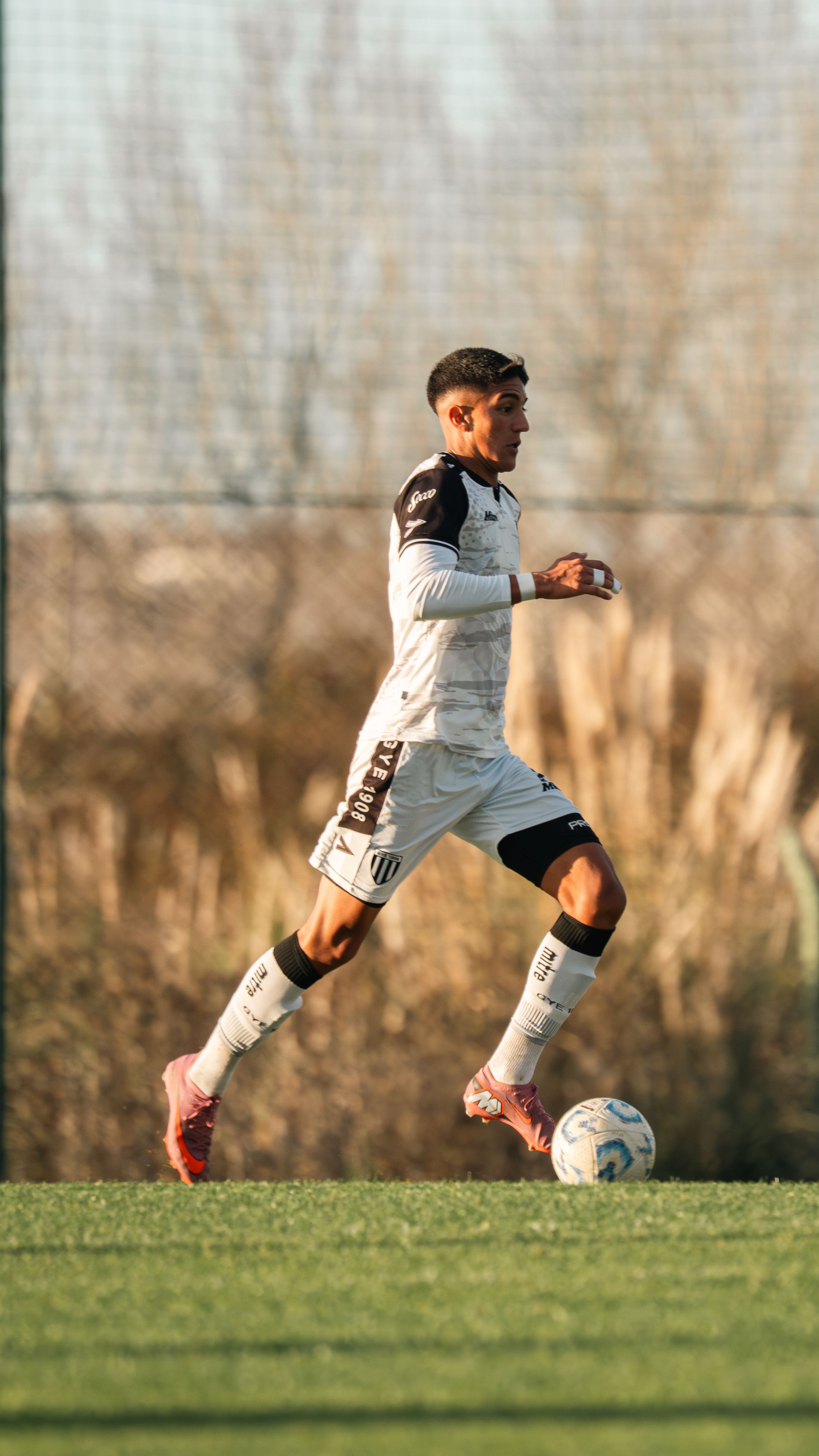 Focused soccer player dribbles on an outdoor field. Training session captured during daylight.
