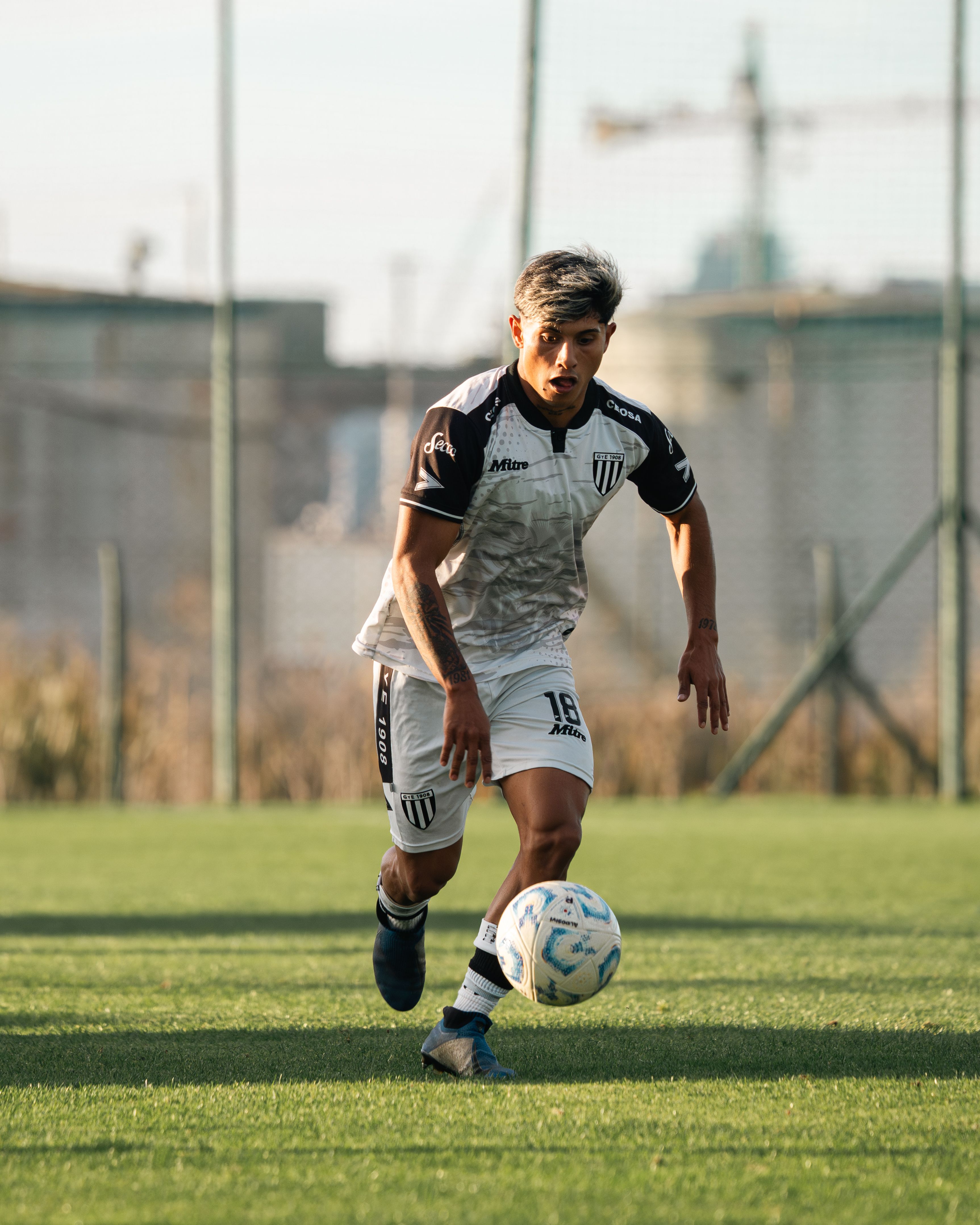 Dynamic action shot of a soccer player dribbling during a game on a sunny day.