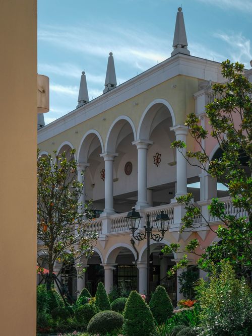 Free Elegant Mediterranean building with arches and spires surrounded by lush greenery on a sunny day. Stock Photo