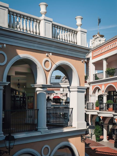Free Mediterranean style shopping complex with arches and columns in a sunny setting. Stock Photo