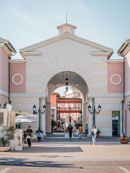 A vibrant outdoor shopping center with beautiful archway, people, and hanging lanterns.