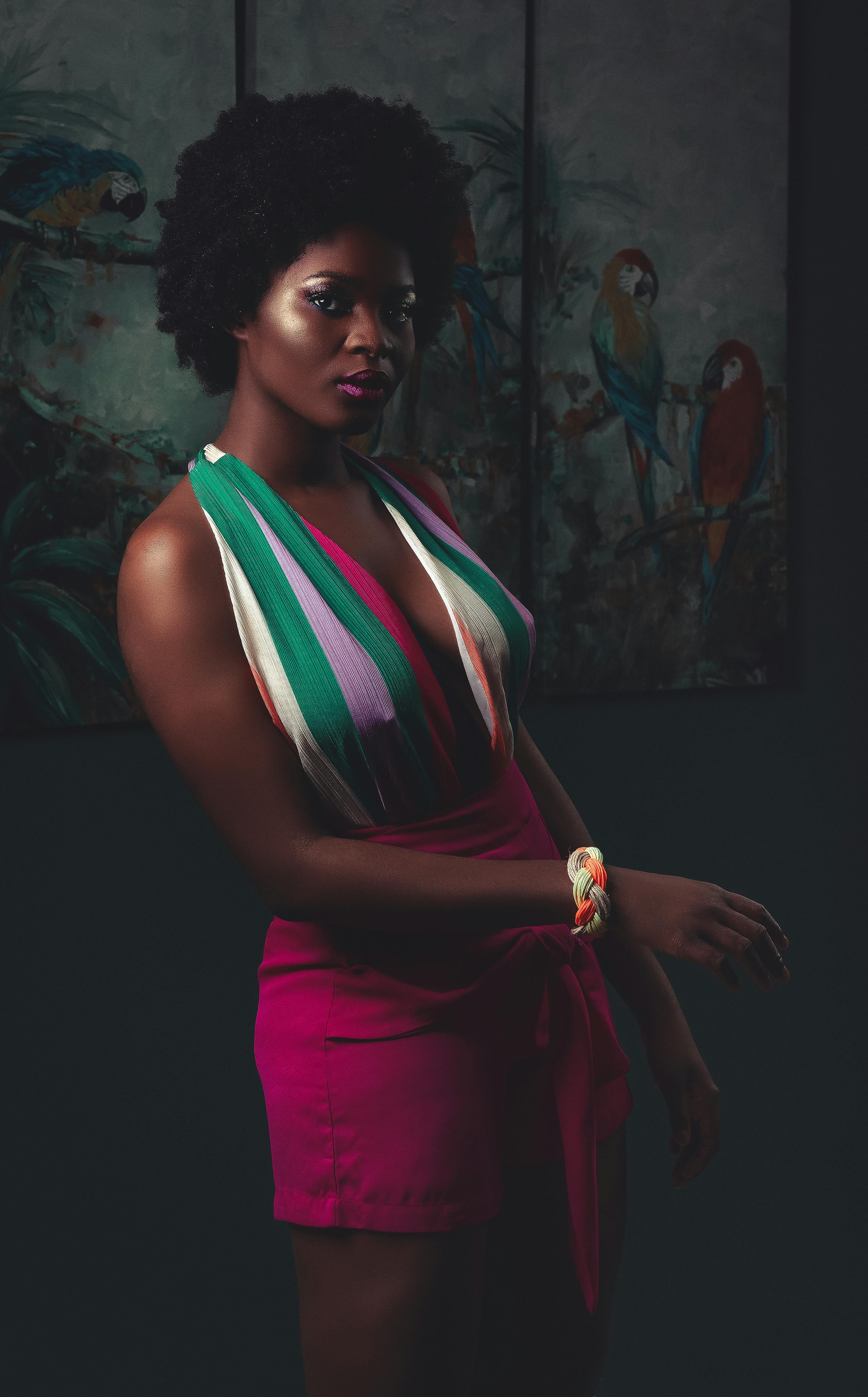 Striking portrait of an elegant woman with afro hairstyle in vibrant attire indoors.
